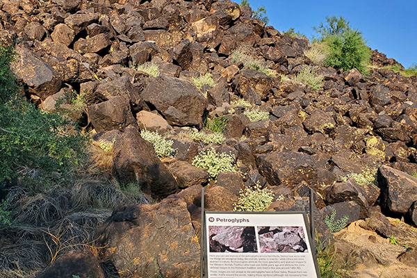 A hill with various rock art and an informational display in front