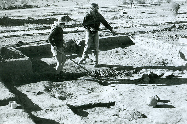 Two men excavating a spot of land with shovels in an archival photo