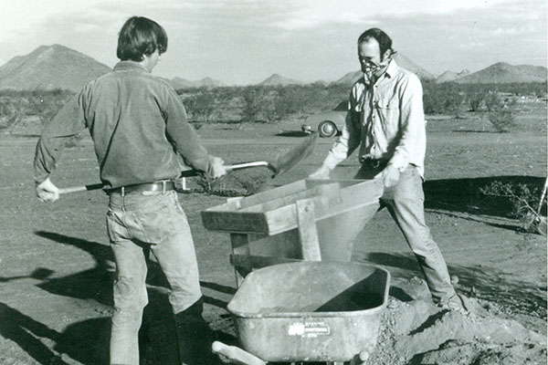 Two men dig and sift dirt in an archival photo