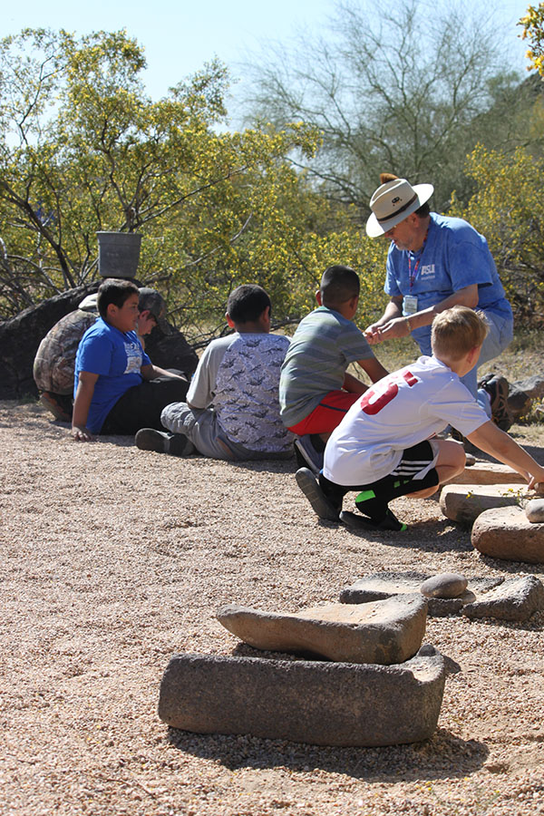 A group of children sitting outside while a volunteer gives directions
